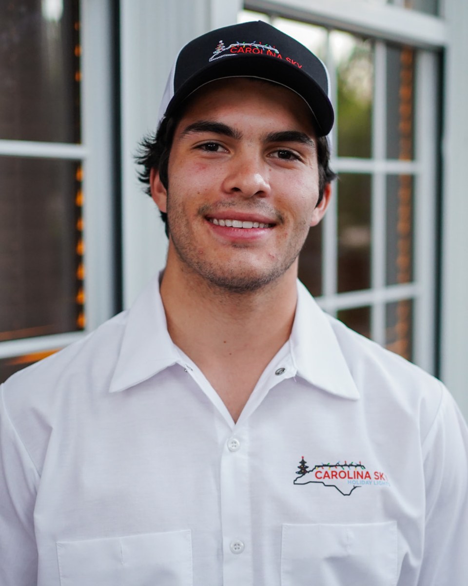 Henry from Carolina Sky Holiday Lights wearing the company shirt and hat